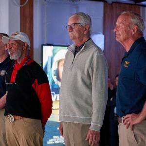 Four people stood in a line looking in the same direction 