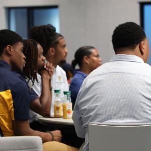 Students sat at a table looking towards the front of the room