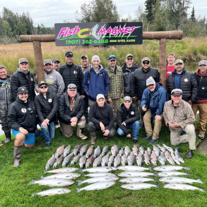 Group posing behind caught fish on the grass