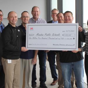 People standing, holding an oversized check
