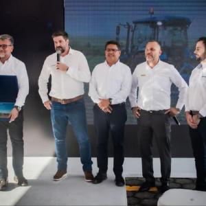 People stood on stage, one person talking in to a microphone and another holding a portfolio