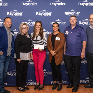 Six people standing together, one holding a check