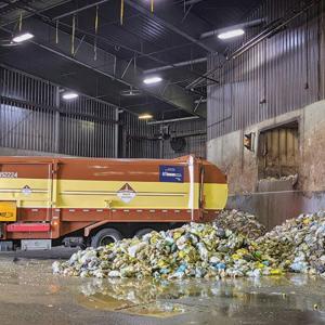 Garbage truck in a bay next to piles of garbage