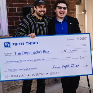 Two smiling people holding an oversized check