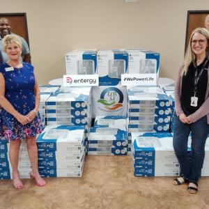 People standing next to stacks of new fans in boxes