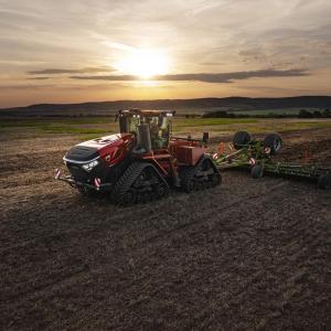 Red tractor on a field with a sunset behind it