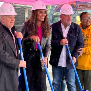 Four people standing together with shovels and hardhats in a breaking ground ceremony