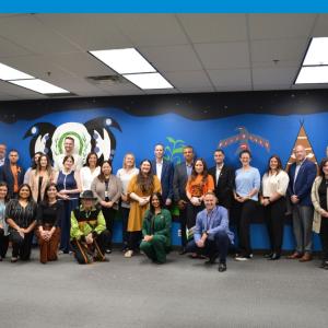 A group of people posing in front of a large mural