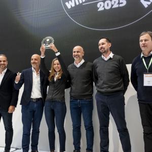 Six people posing together, one holding up an award