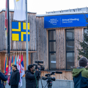 A building with Alps in the background, and people gathering outside