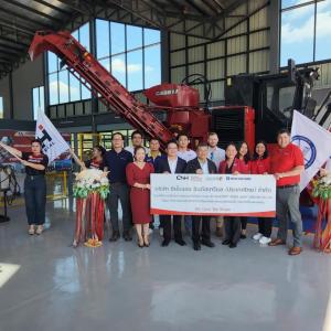 A group of people stood in front of agricultural machinery 