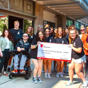 A group of people posing and smiling with an oversized check