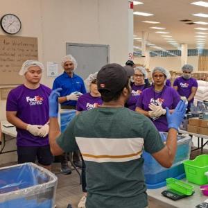 People in FedEx t-shirts and hair nets listening to someone