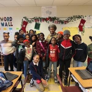 Students and teacher stand in front of classroom