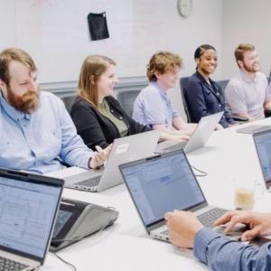 People sitting at a conference table working on laptops