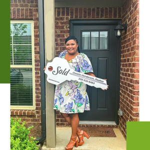 Person standing outside a house's front door, holding a large key
