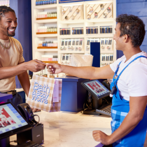 A Bath & Body Works employee handing a bag across the counter to a customer