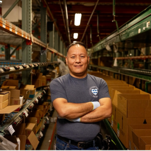 A person standing in a warehouse surrounded by shelves and boxes