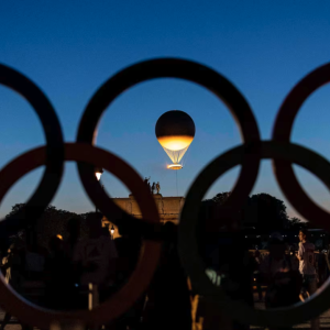 Olympic rings in silhouette with a lit balloon in the center