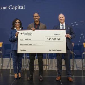 Three people holding a large check