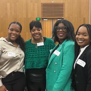 Four people stand together smiling