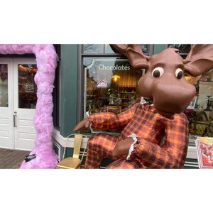 A giant chocolate moose "sitting" in front of a store