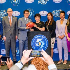 People on a stage behind a podium holding a football