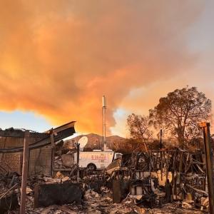 Burnt rubble and trees in front of a smoke-filled sky