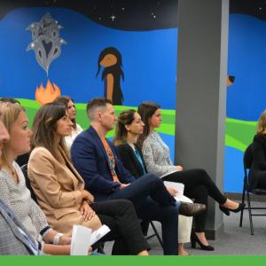 People seated at a presentation, with a large mural in the background