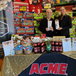 A person and person standing next to a table with food items