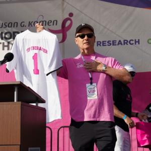 Man holding t-shirt jersey with #1 and Top Fundraiser on back.