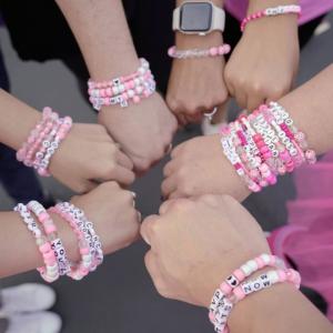 Picture of arms with pink friendship bracelets.