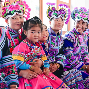 A group seated in a row, each wearing colorful, detailed cultural garments.