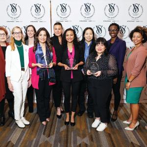 A group of women, 3 holding glass awards, in front of a VS Global Fund for Women's Cancer backdrop
