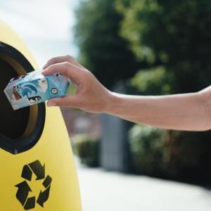 a carton being thrown into a yellow recycling bin