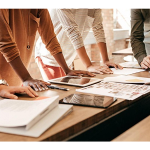 Four individuals leaning over a desk with papers on it