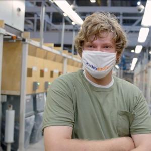 Image of a man in a green t-shirt wearing a mask over his nose and mouth