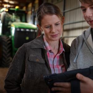 two people looking at a computer screen in a barn