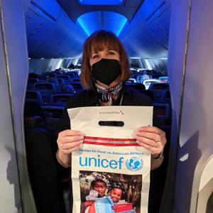 Flight attendant holds up a UNICEF donation bag
