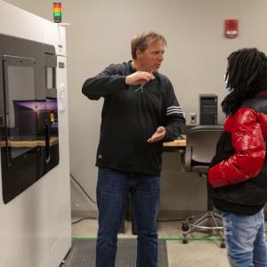 Whirlpool mentor talks with Benton Harbor High School student in front of a wall-mounted appliance