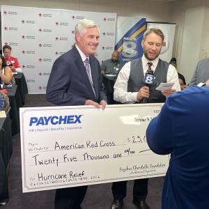 Man holding big check of donation from Paychex
