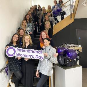 Women on staircase holding International Women's Day sign