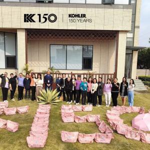 Group of people standing behind bags arranged to spell out K 150
