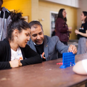 Balaji Ganapathy plays connect four with two students 