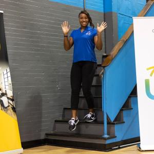 Volunteer walks downstairs waving both hands