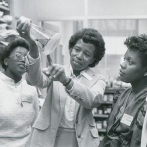 Five people examining a beaker