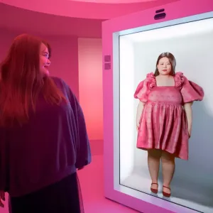 A person stood in front of a screen displaying an AI avatar 