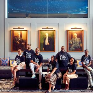 People collected together in front of three paintings