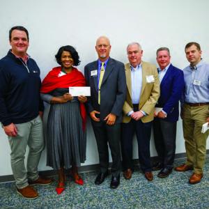 People standing together, one holding a check