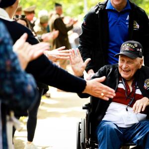 People clapping and reaching out to a war veteran 